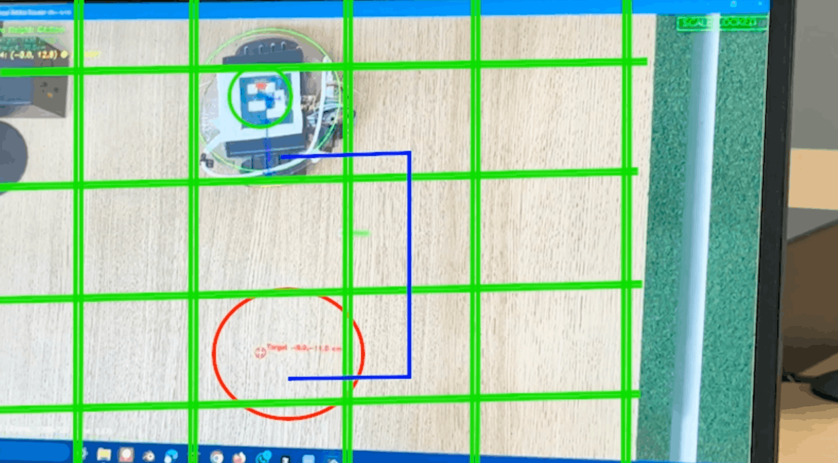 Live green-grid camera tracking demo showing robot coordinates on a tabletop test surface